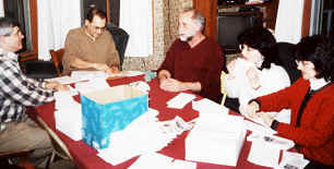 Photo of BLC helpers sitting around table, folding and mailing newsletters.