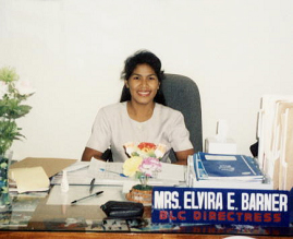 Photo of Elvie sitting at her desk, smiling.