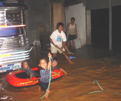 Kids in boat with two adults trying to deal with muddy flood water in the BLC gym
