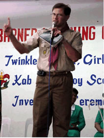 Paul in scout uniform, talking into microphone.