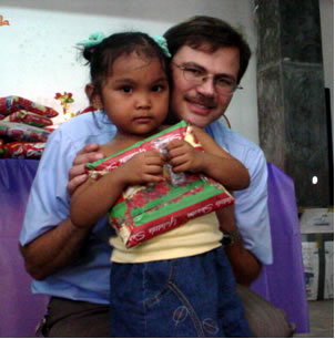 Paul with a Filippino child, holding a gift.