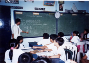 Teacher at chalkboard in front of class of children
