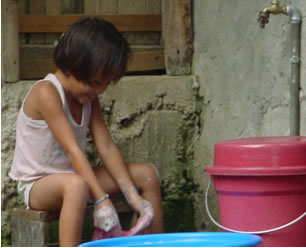 Small girl scrubbing laundry in a bucket