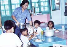 Woman dishing food with four children